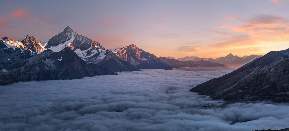 Alpine Lake at First Light: snow peaks glowing above a sea of clouds at dawn