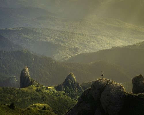 Mountain Light: sunlit ridges and sculpted rocks, with a tiny figure on a peak